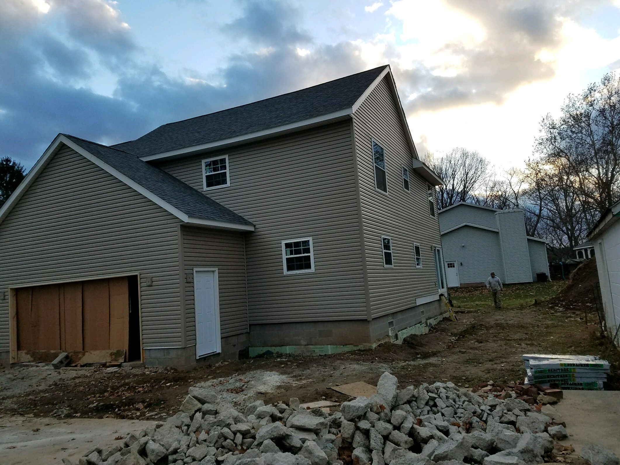 Sided house with attached garage, garage opening temporarily boarded.