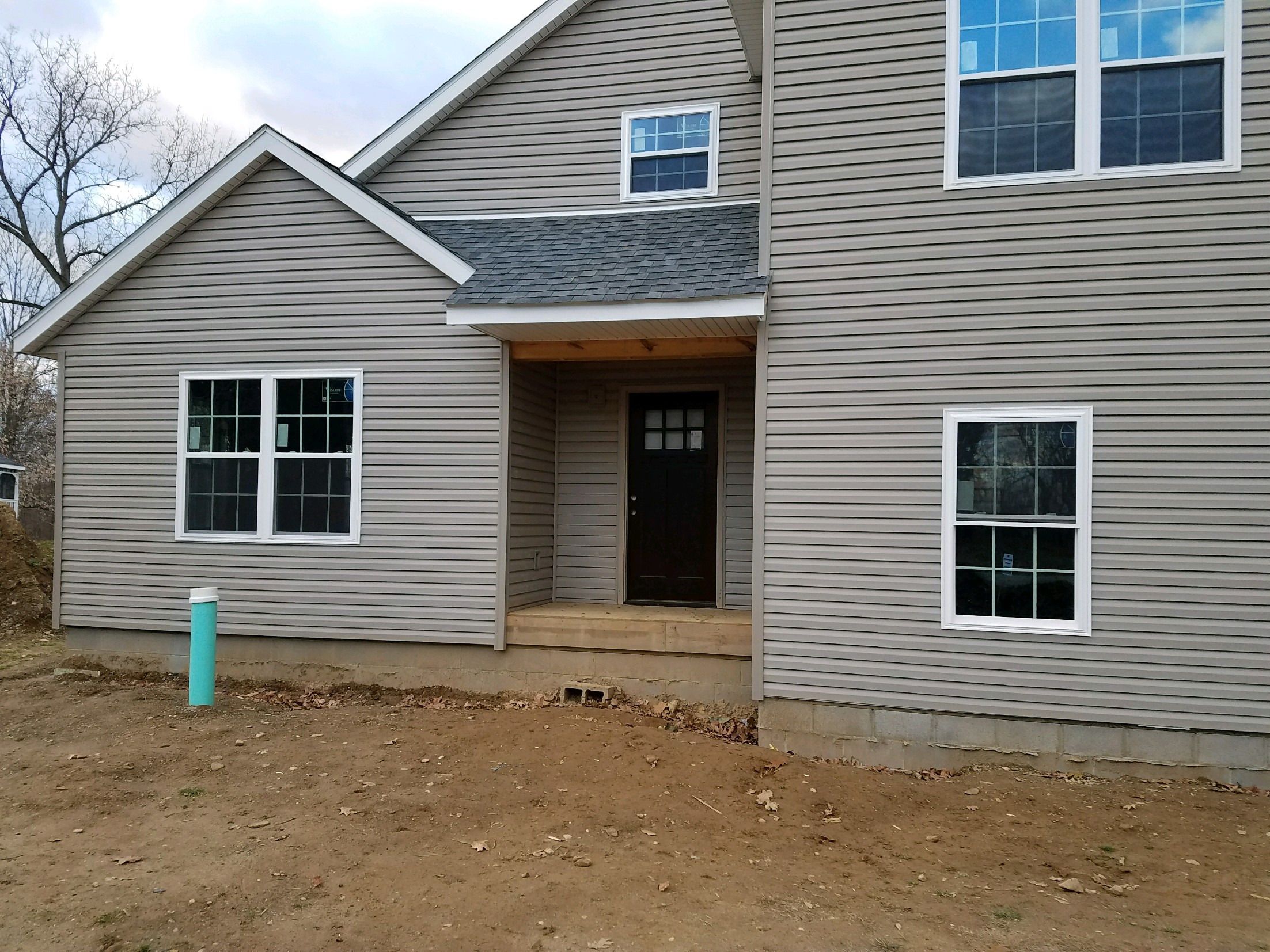 Front entry of the new home with covered porch and dark front door.