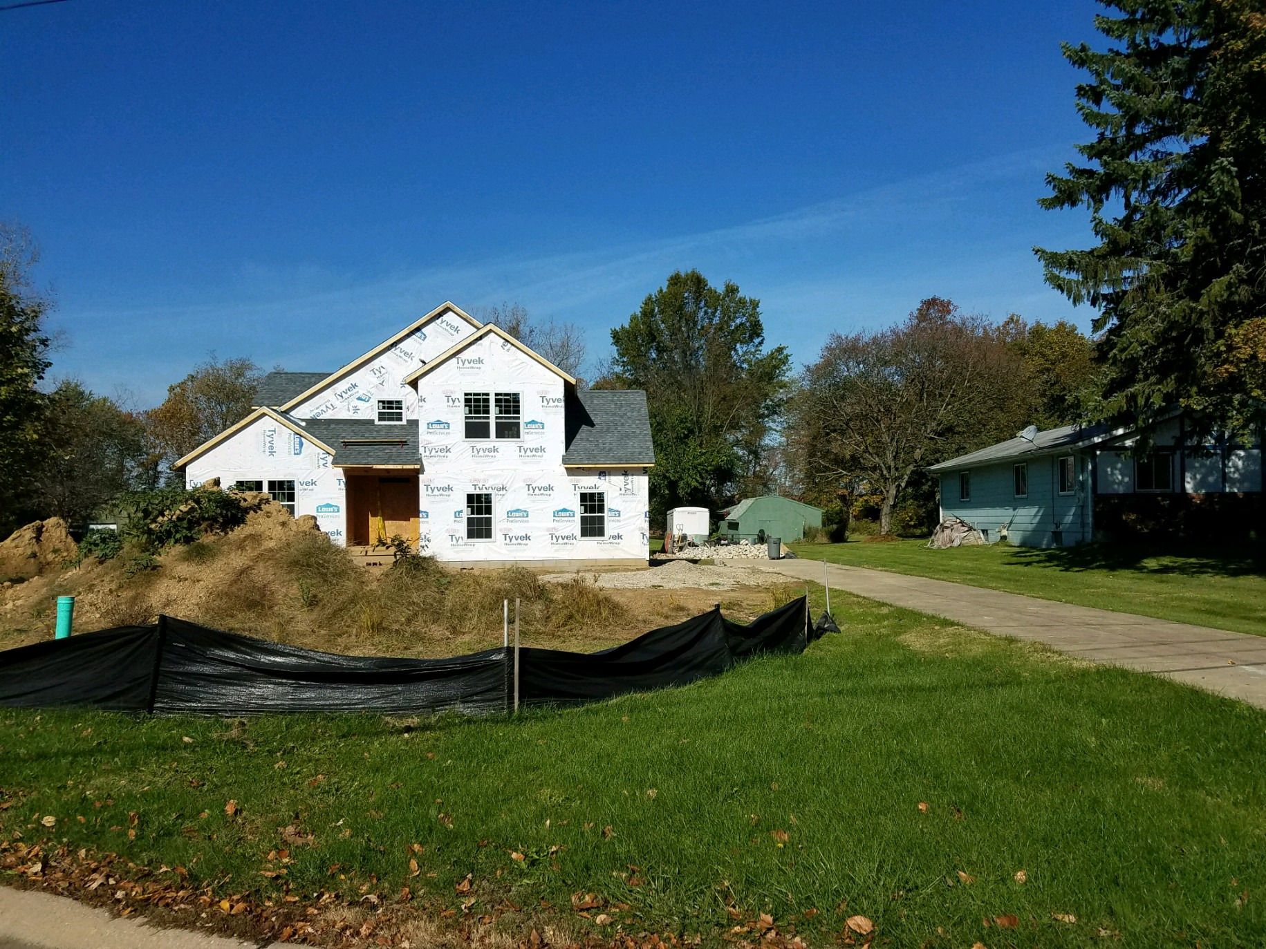 Street view of the house with roof shingled and walls still in house wrap.