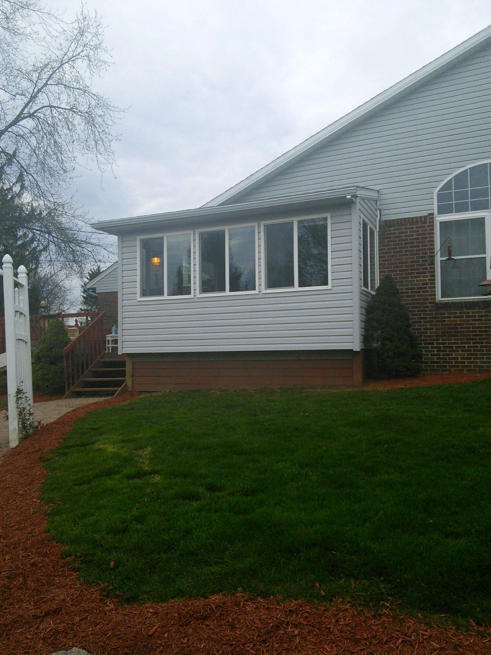 Finished sunroom addition on the back of a house, with a row of new windows.