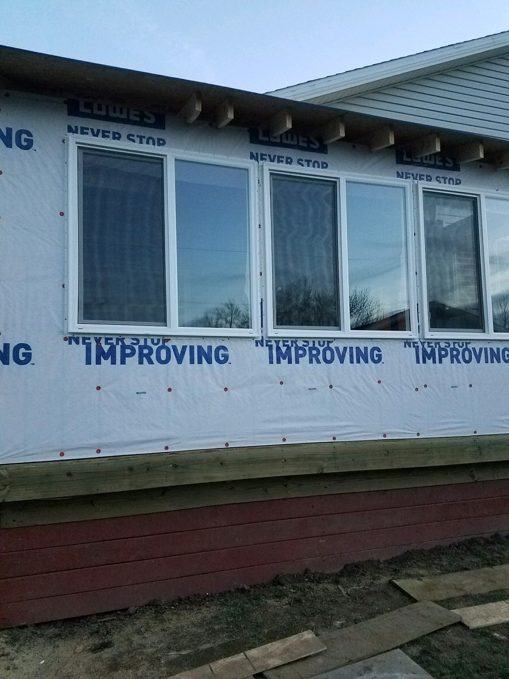 Exterior with new windows installed and house wrap on the walls.
