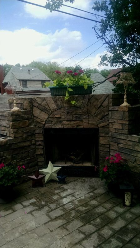 Front view of the stone fireplace with planters and flowers on top.