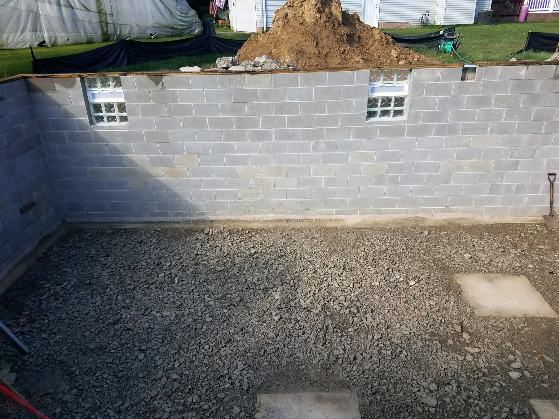 Finished block basement walls with glass block windows and a gravel floor base.