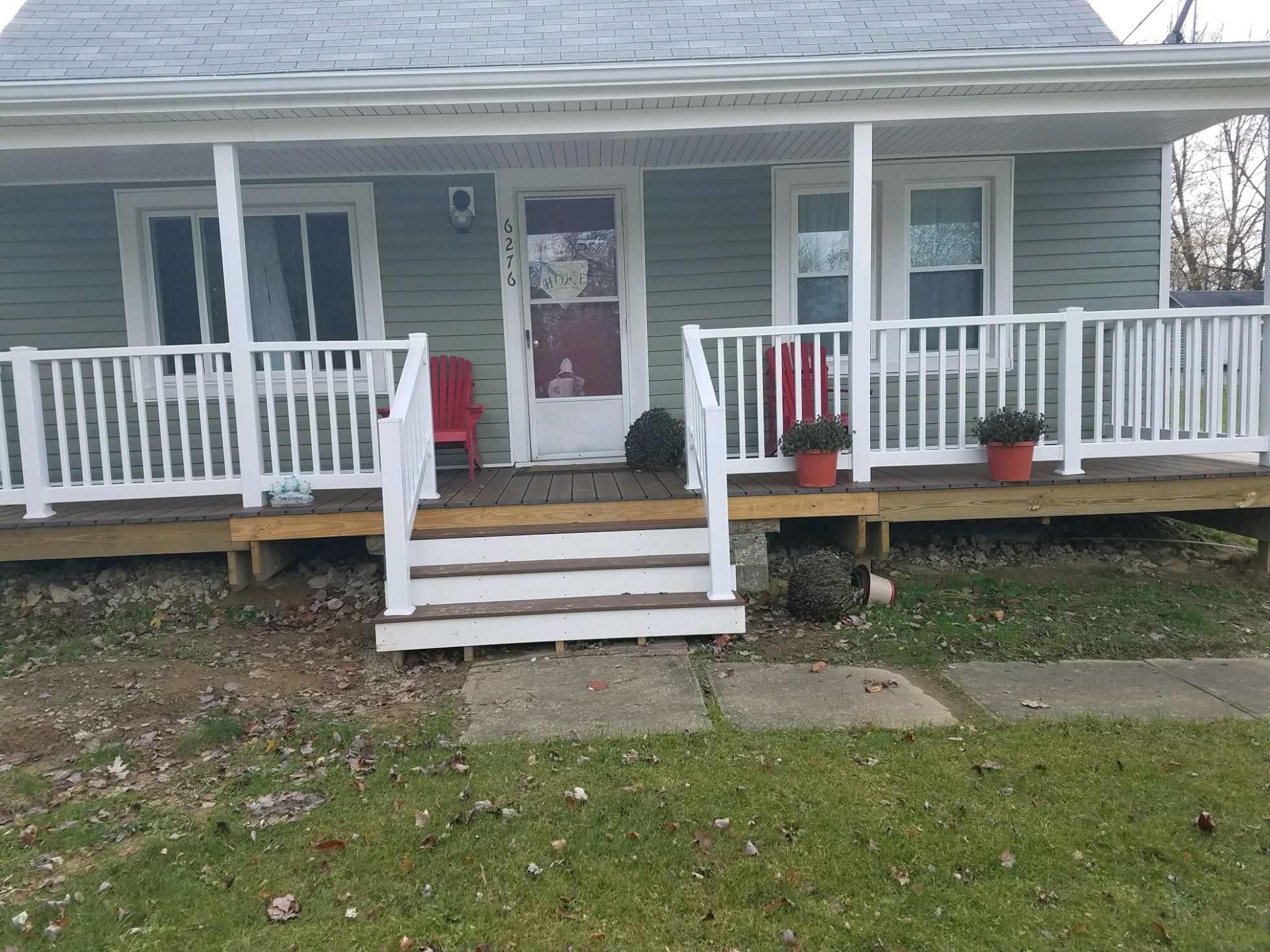 Front porch with a new wood deck, white railings and steps leading to the front door.