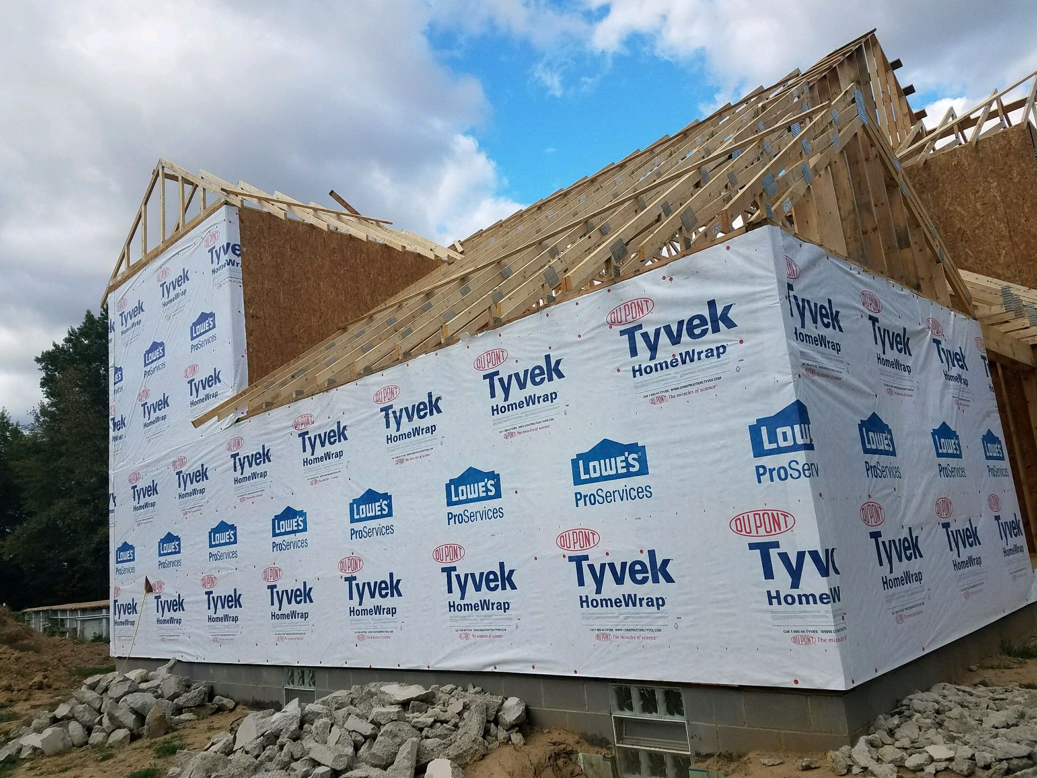 Side of the house fully wrapped, with roof trusses and sheathing in place.
